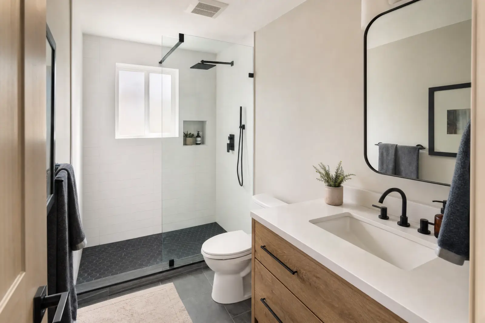 A remodeled bathroom with a walk-in glass shower and a wood vanity