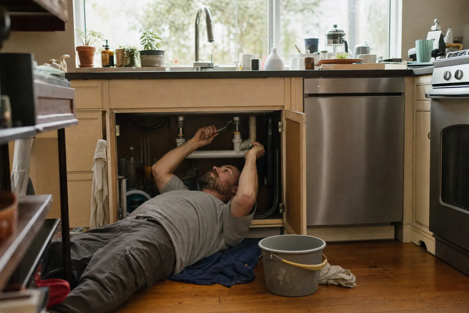 A plumber fixing the pipes under a kitchen sink